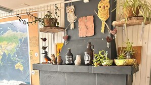 A cozy living room with a fireplace, a map on the wall, and various decorative items. - Casa Piwke (Coyhaique)
