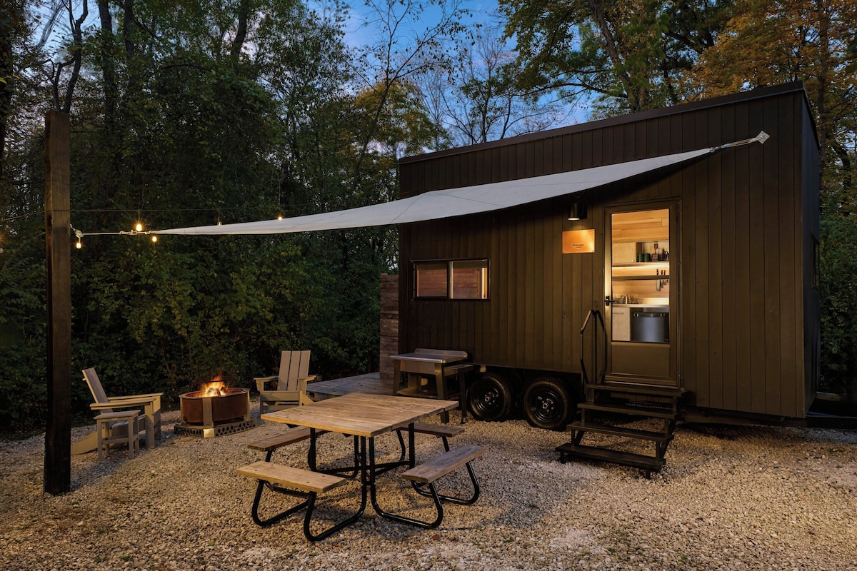 Un chalet rustique doté d’un coin repas, d’un espace extérieur aménagé et d’un foyer.