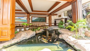 A hotel lobby with a koi pond, wooden furniture, and a large painting.