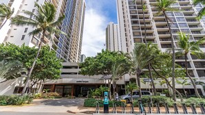 A high-rise hotel with multiple floors, palm trees, and a clear sky.