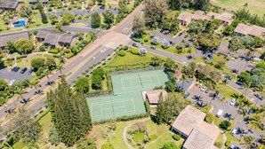 Vue aérienne d’un quartier résidentiel comprenant plusieurs maisons, un court de tennis et un parking.