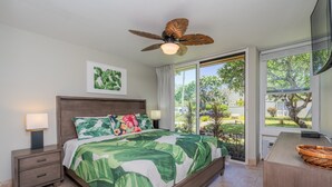 Une chambre à coucher avec un lit, une table de chevet, un ventilateur de plafond et une vue sur l’extérieur.