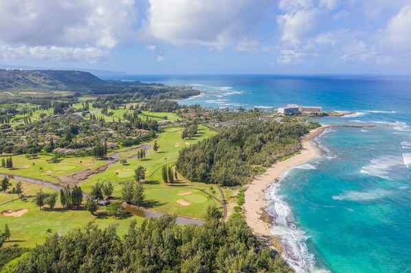 Vista aérea de un campo de golf frente al mar, con playa y océano.