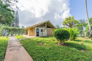 A small, single-story building with a stone facade and a sloped roof, surrounded by lush greenery and a clear sky. - 🍧Summer Special - Welcome to Gorgeous Hideout – Your Serene Hawaiian Escape! 🏄‍♂️ (Kahuku)