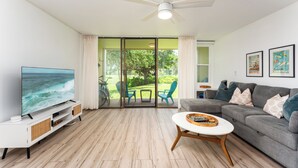 Una sala de estar con televisor, sofá, mesa de centro y ventilador de techo.