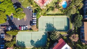 Vue aérienne d’un complexe de courts de tennis, avec un parking attenant et une piscine.