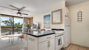 Une cuisine moderne dotée d’un îlot central, de meubles blancs, d’un réfrigérateur et d’un ventilateur de plafond.