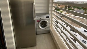 Un petit balcon équipé d’un lave-linge et d’un réfrigérateur.