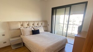 Une chambre avec un grand lit, une table de chevet, un plancher en bois et une vue sur l’extérieur grâce à une porte coulissante.