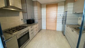 Une cuisine moderne équipée d’une cuisinière à gaz, d’un four, d’un four à micro-ondes et de meubles de rangement en acier inoxydable.