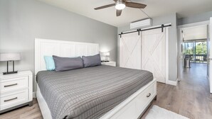 Een slaapkamer met een groot bed, een plafondventilator, een witte kledingkast en uitzicht op de omgeving.