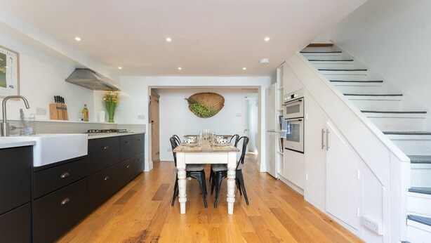 Una cocina moderna con una mesa de comedor, piso de madera y una escalera.