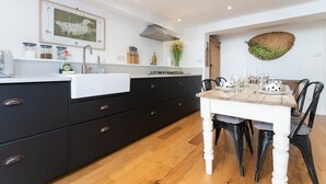 Una cocina moderna con gabinetes negros, encimera blanca y una mesa de comedor para cuatro personas.