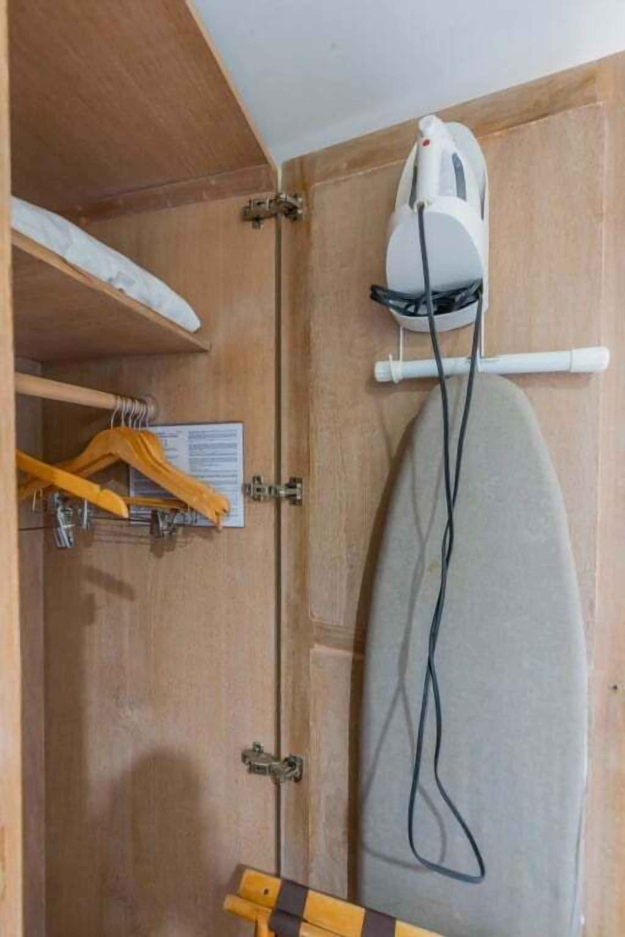 Une armoire en bois avec un fer à repasser suspendu et un cintre en bois.