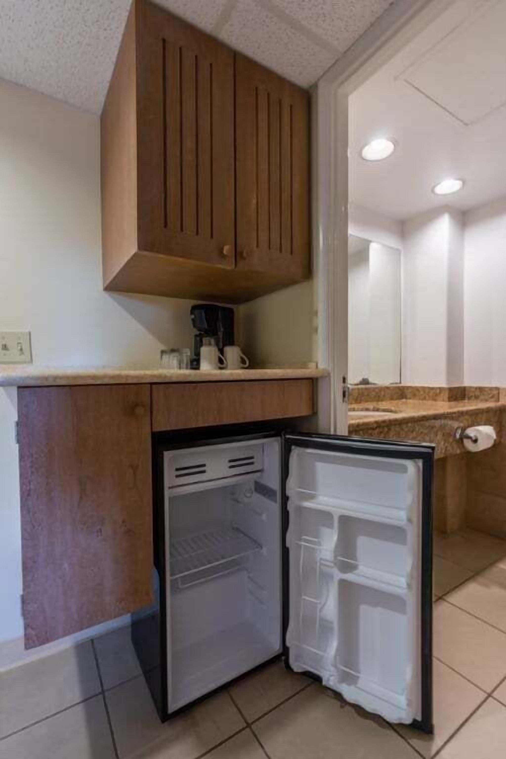 A compact kitchen with a built-in refrigerator, wooden cabinets, and a countertop.