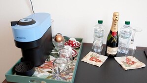 Une machine à café, deux bouteilles de champagne LeVissima et un plateau avec des verres et des assiettes.