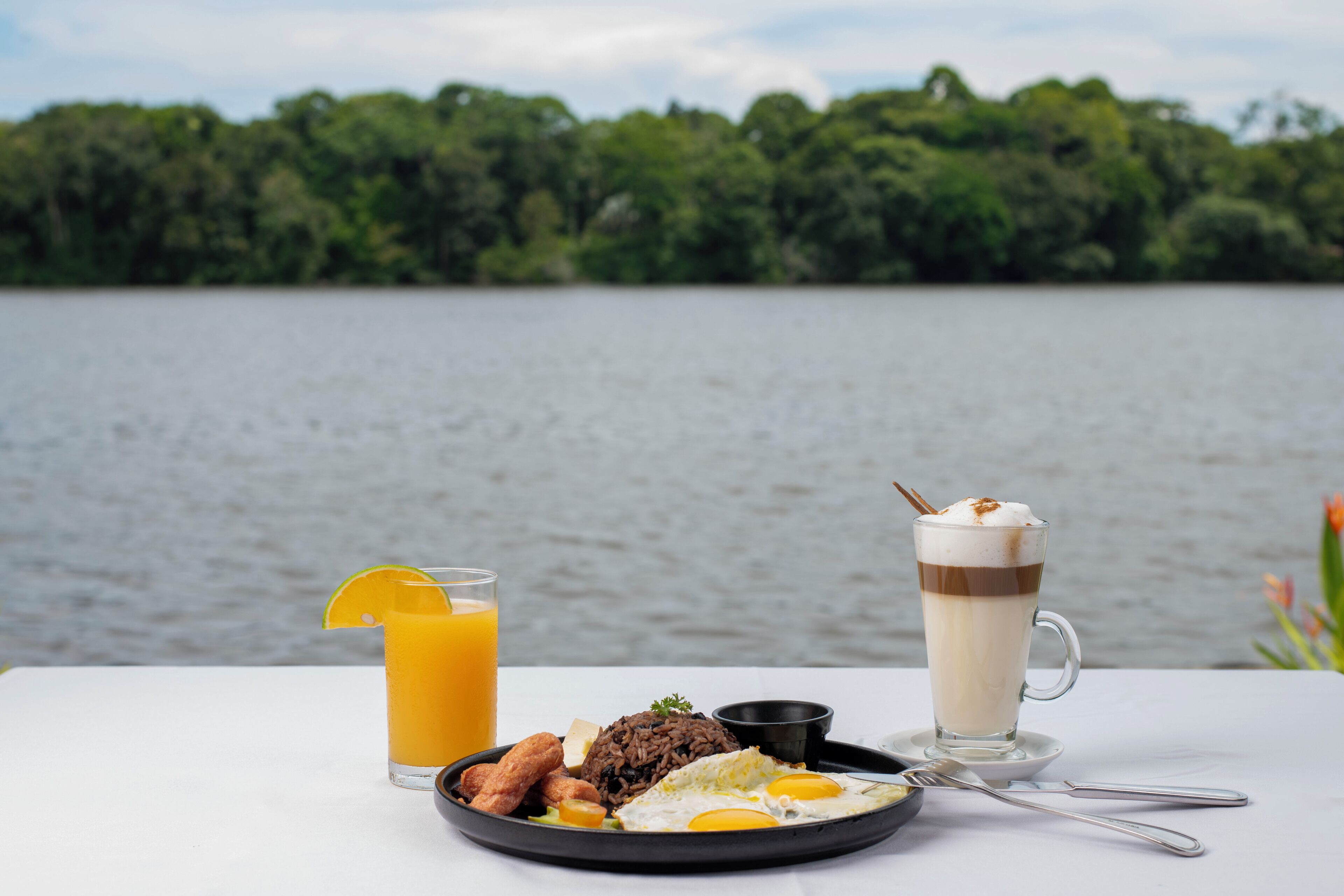 Un repas avec une boisson et une tasse sur une table au bord d’un lac.