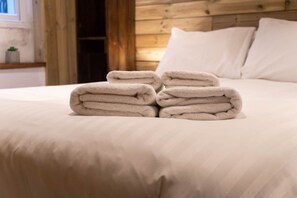 A neatly made bed with folded white towels in front of it. - Host Stay Grafton Woodshack (Brighton)