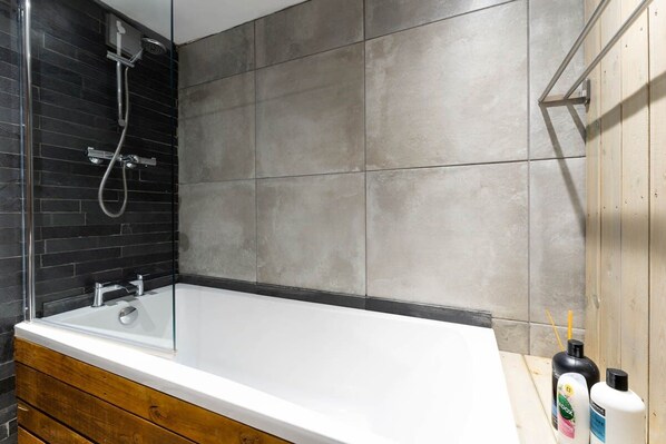 A modern bathroom with a glass-enclosed shower, a white bathtub, and wooden cabinetry. - Host Stay Grafton Woodshack (Brighton)