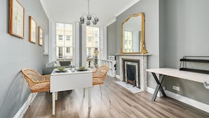 A modern living room with a white dining table, wicker chairs, a fireplace, and a large mirror on the wall. - Host Stay Sea View Oriental Place (Brighton)