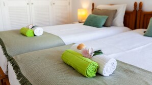 Habitación de hotel con dos camas, cada una con una toalla verde y una flor.