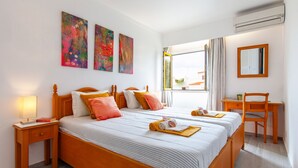 A hotel room with a double bed, a desk, a chair, and a window with curtains. - Charming apartment at Vilamoura Marina (Quarteira)