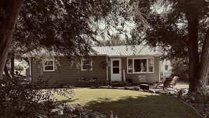 Ein kleines Haus mit Veranda, umgeben von Bäumen und einem Rasenstück.