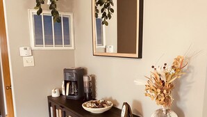 Eine moderne Küche mit einem dunklen Holsschrank, einer Kaffeemaschine und einer Vase mit Trockenblumen.