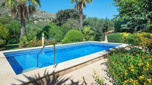 A rectangular swimming pool with a tiled edge, surrounded by lush greenery and flowering plants. - Can Piña - Two Bedroom Villa, Sleeps 4 (Mallorca)