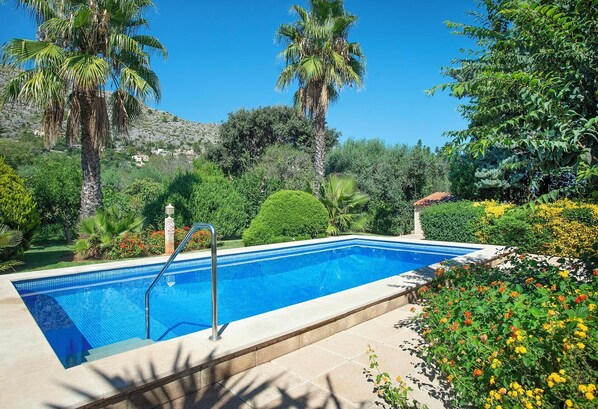 A rectangular swimming pool with a tiled edge, surrounded by lush greenery and flowering plants. - Can Piña - Two Bedroom Villa, Sleeps 4 (Mallorca)