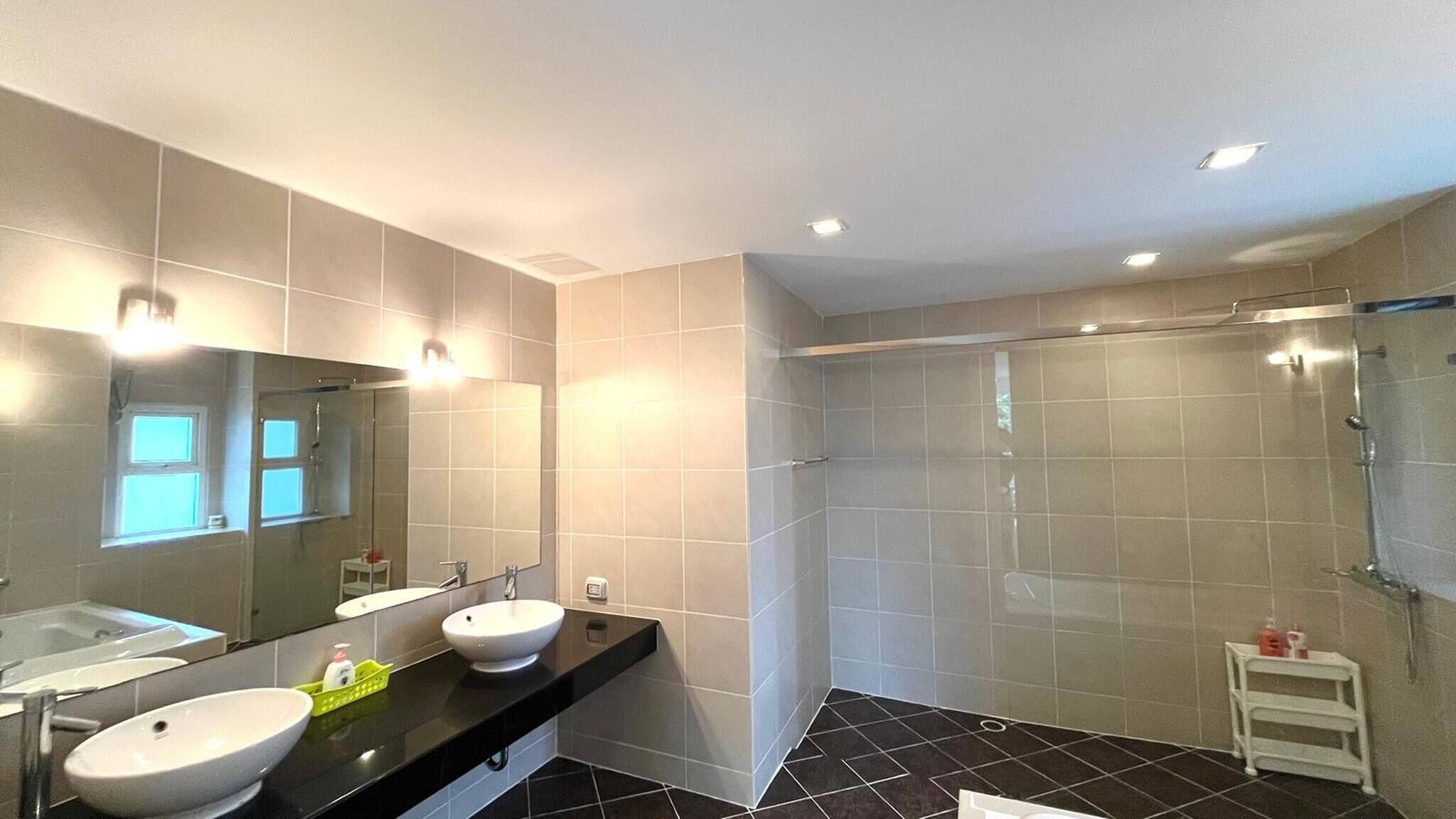 Un bany modern amb dues dutxes, un mirall gran i una platja de banyera.
