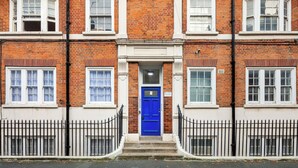 A red brick building with a blue door, white windows, and a black metal fence. - |Elegant Three Bed Apt in The Heart of Marylebone| (London)