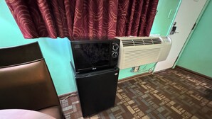 A compact room with a patterned floor, a small black refrigerator, a wall-mounted air conditioner, and a curtain with a swirl pattern. - #33 Nice stay near Bexley and Capital University (Columbus)