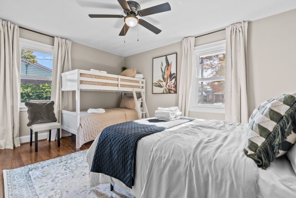 A bedroom with a bunk bed, a desk, and a ceiling fan.