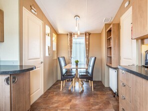 A modern kitchen with a dining table, chairs, and a view of the outside.