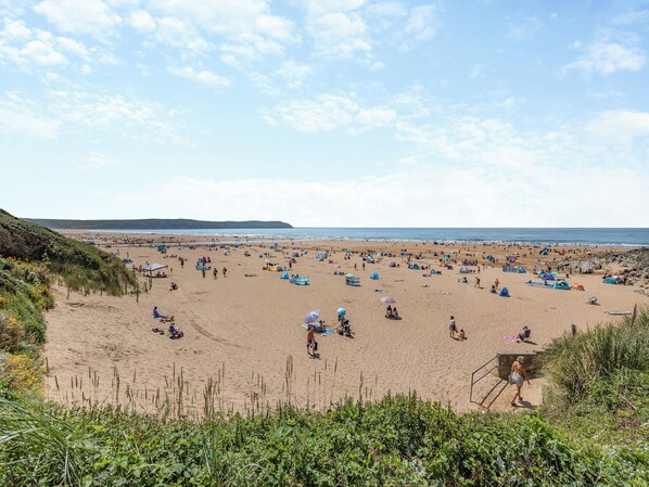 A beach with tents and people, a lifeguard tower, and a distant shoreline.