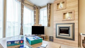 A hotel room with a large window, a flat-screen TV, a fireplace, and a desk with a board game. - 2 bedroom accommodation in Ilfracombe (Ilfracombe)