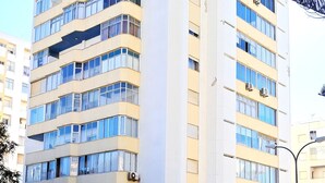 A multi-story building with a modern architectural design, featuring a prominent vertical element and a series of balconies. - T1 Torre Azul 10 A C Vista Mar e Praia (Loulé)