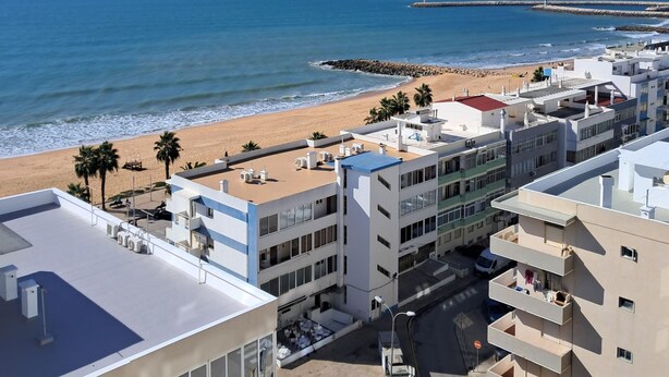 A coastal urban area with modern buildings, a beach, and a pier. - T1 Torre Azul 10 A C Vista Mar e Praia (Loulé)