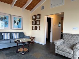 A living room with a sofa, a patterned armchair, a round table, and artwork on the walls.