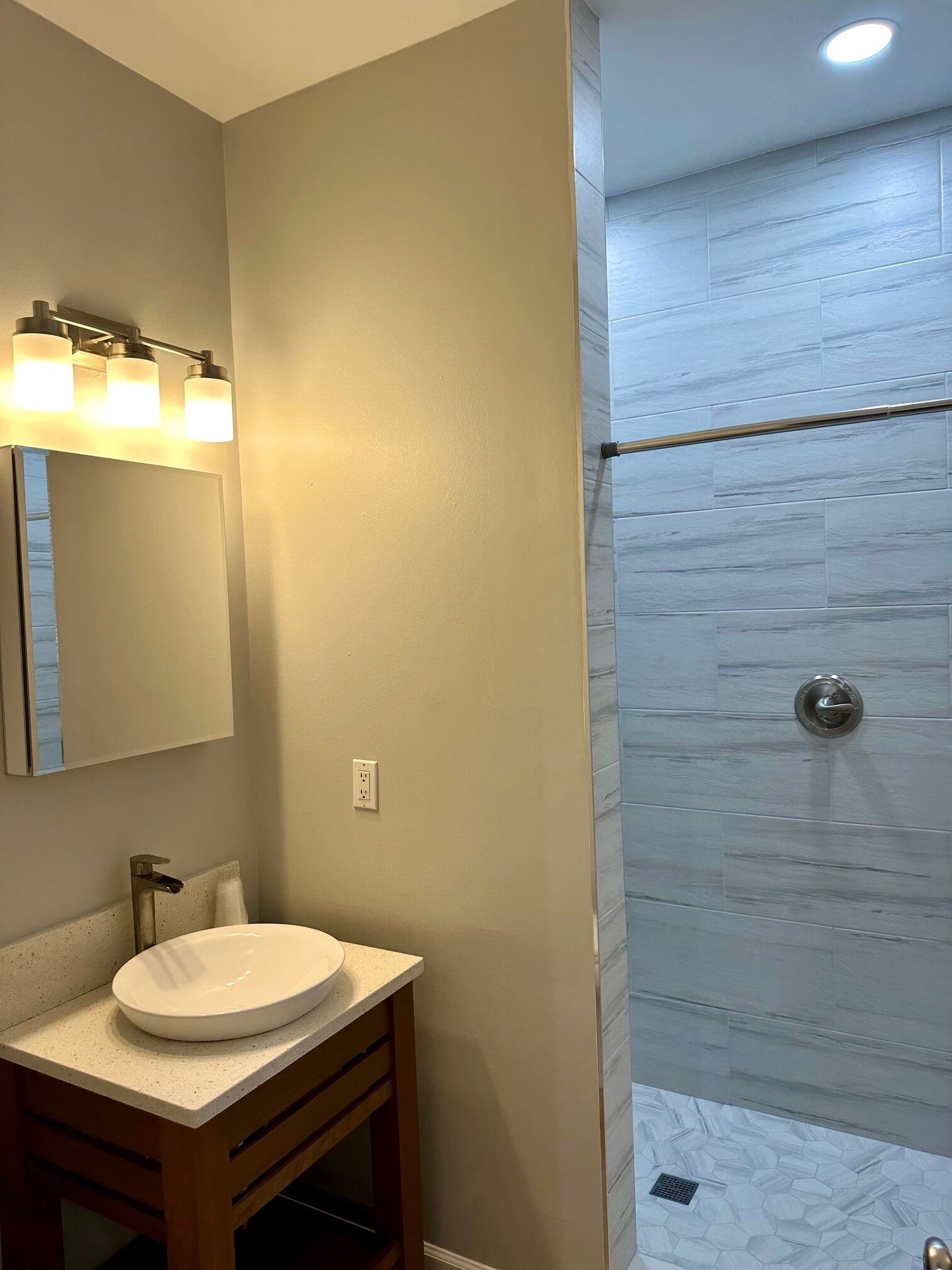 Een badkamer met een wastafel, spiegel en douche met glazen deur.