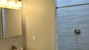Een badkamer met een wastafel, spiegel en douche met glazen deur.