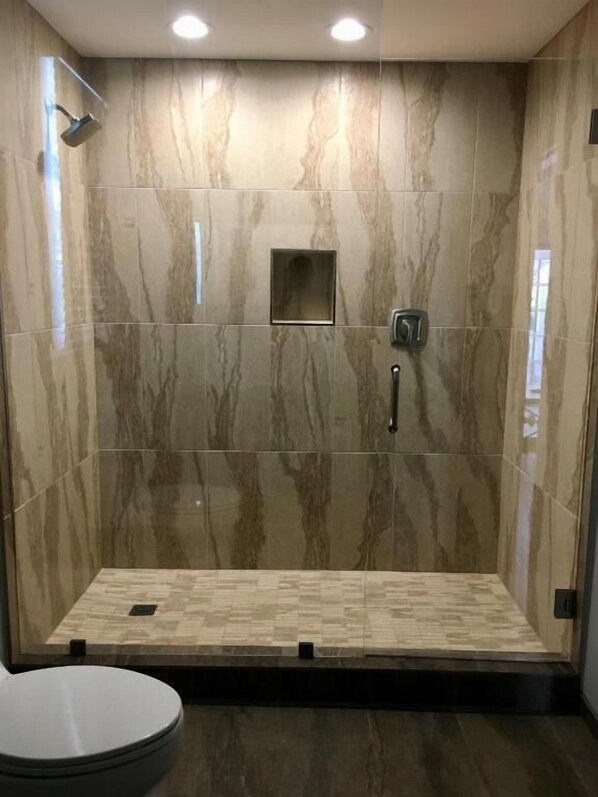 A modern bathroom with a walk-in shower, marble walls, and a toilet. - Douglas House - Adults Only (Key West)