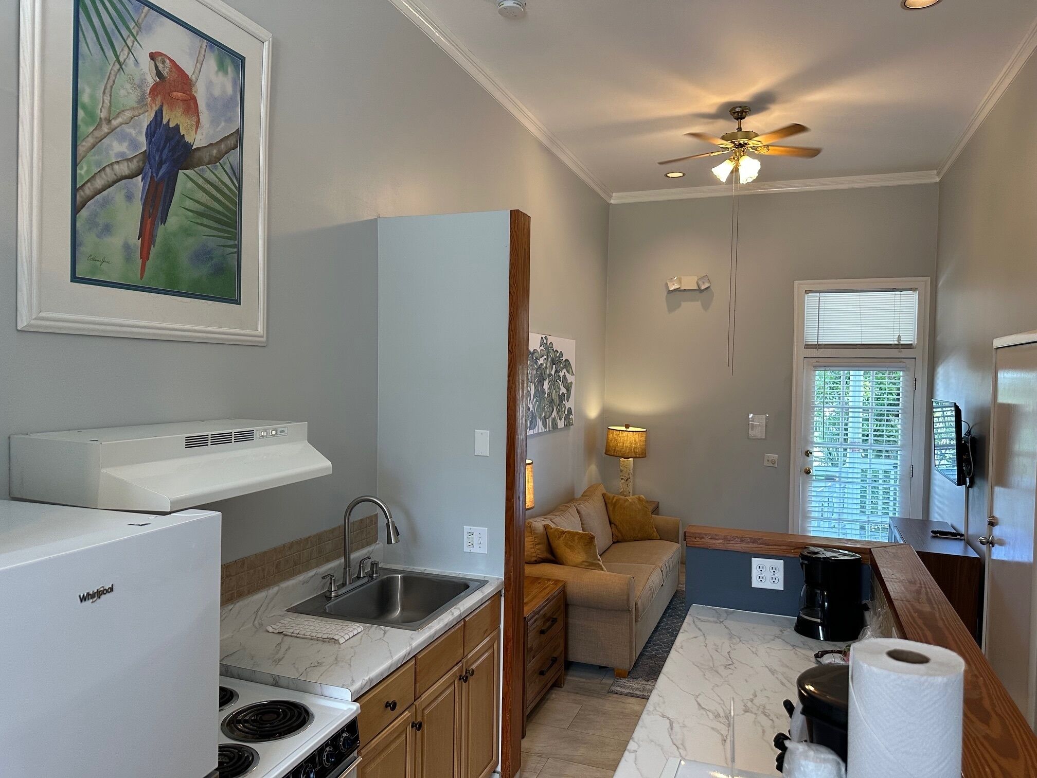 A compact kitchen with a built-in stove, sink, and a ceiling fan.