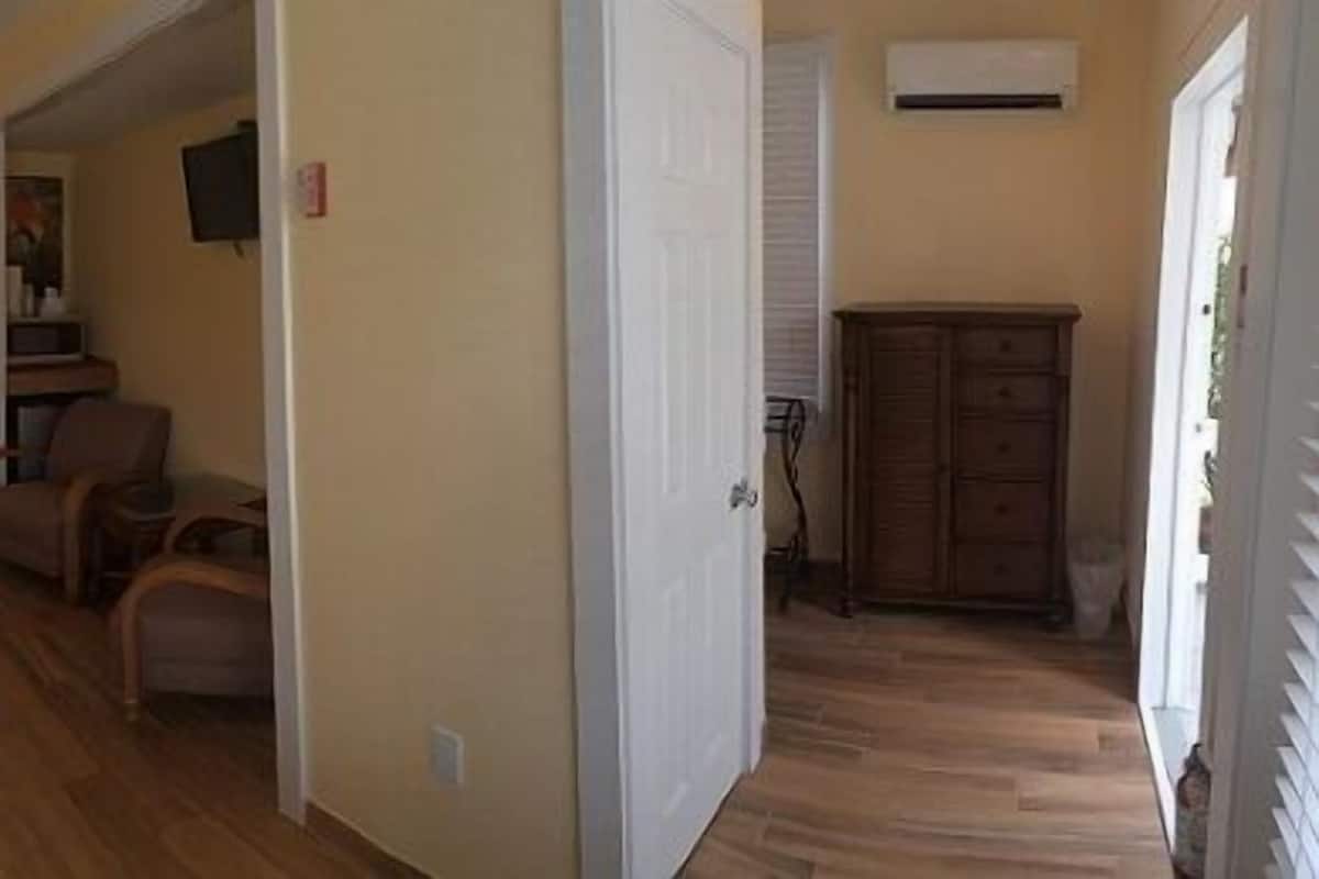 A hotel room with two beds, a desk, a chair, and a painting on the wall.