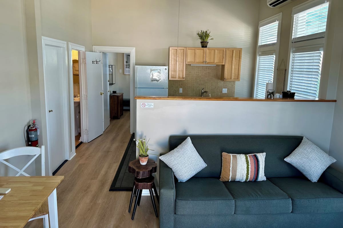 A modern kitchen with wooden cabinets, a built-in fridge, and a small dining area with a table and chairs.
