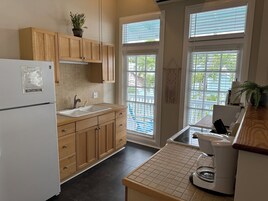 Una cocina compacta con gabinetes de madera, un refrigerador blanco, un lavamanos y una cafetera.