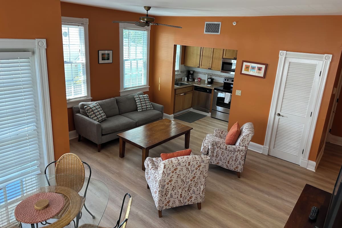 A living room with a sofa, two armchairs, a coffee table, and a dining area with a table and chairs.