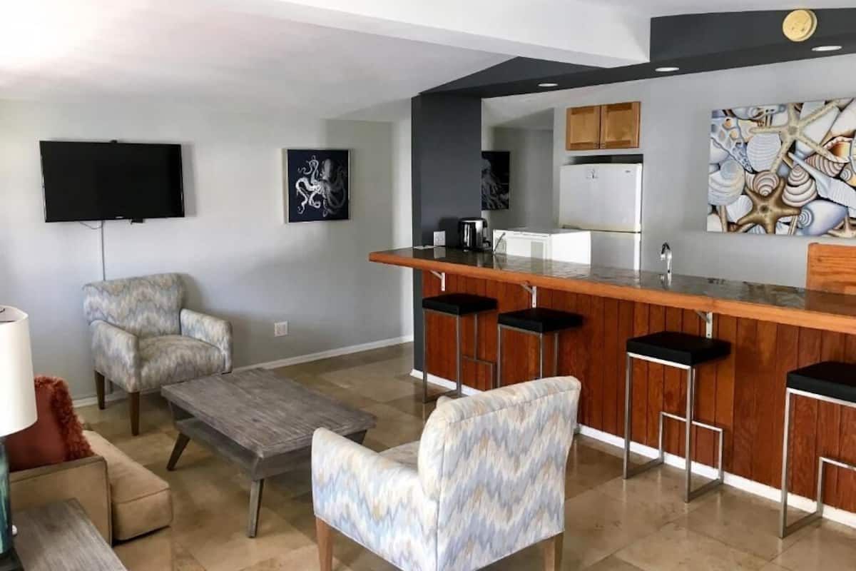 A modern kitchen with a bar area, a flat-screen TV, and artwork on the walls.