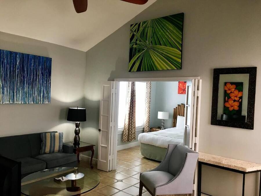 A hotel room with a sofa, a chair, a coffee table, a bed, and a painting on the wall.